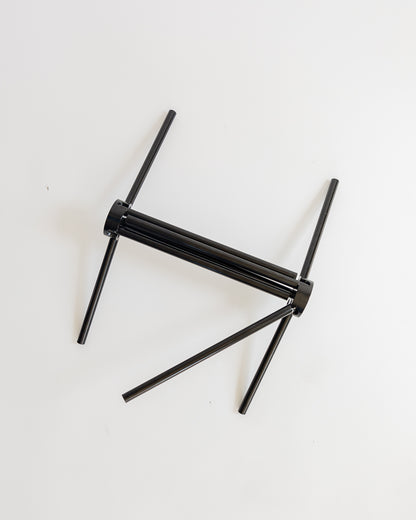 Black metal chair frame partially collapsed on a white background